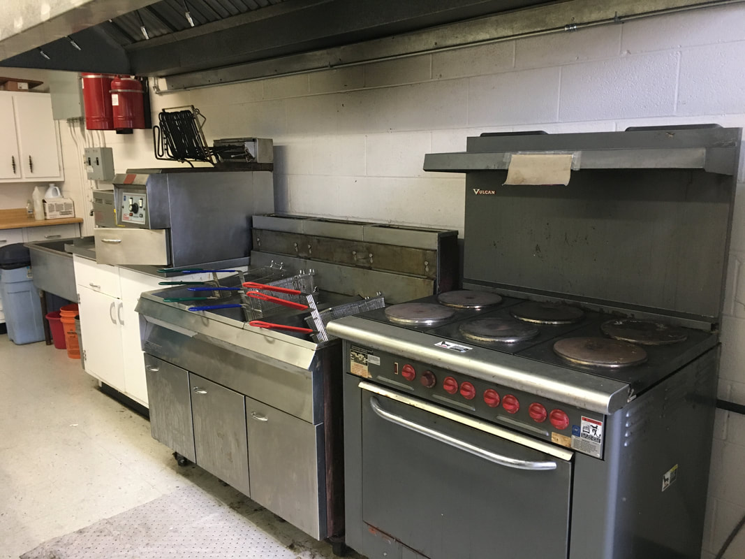 large six-burner stove and deep fryer in a commercial-sized kitchen